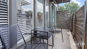 A patio with a table and chairs, large windows, and a stone wall. - Explore Austin Life, Studio Near Guadalupe St (Austin)