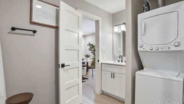 A laundry room with a washing machine and dryer, a sink with a mirror, and a door leading to a dining area. - Explore Austin Life, Studio Near Guadalupe St (Austin)