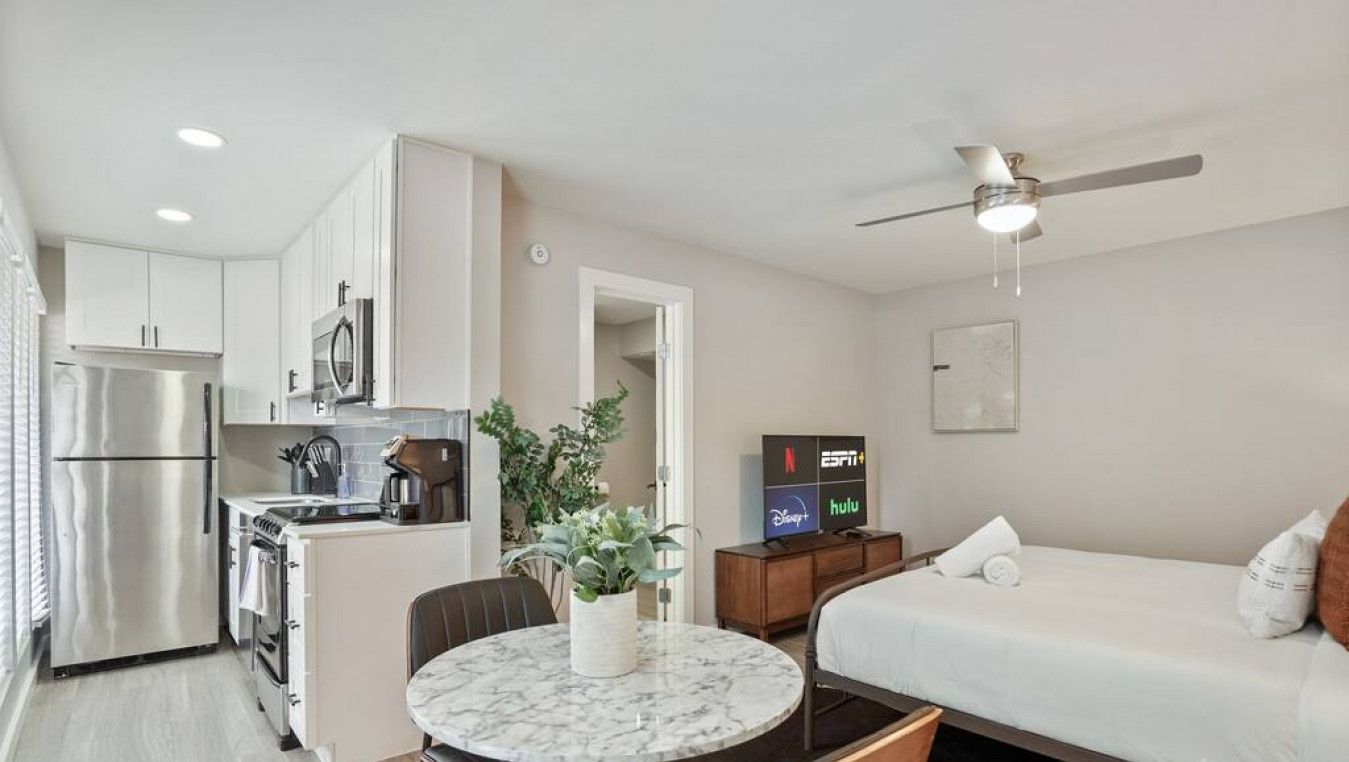 Habitación de hotel compacta con kitchenette, cama, zona de comedor y televisor que muestra servicios de streaming.