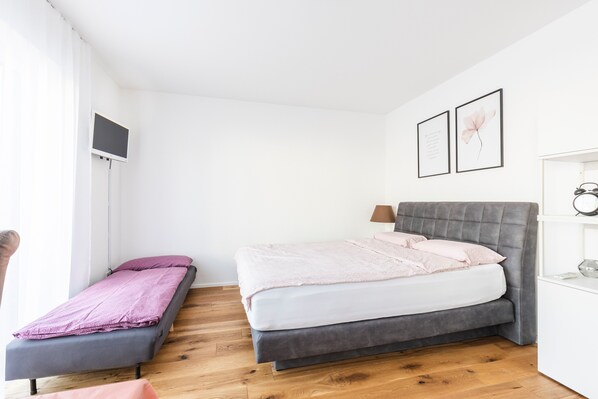 A bedroom with a bed, a bedside table, a lamp, and a TV mounted on the wall.