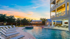 A pool area with lounge chairs, a hot tub, and a covered patio. - The Belvedere - Luxury Vacation Rental Near the Beach with Huge Pool & Volleyball Court (Santa Rosa Beach)