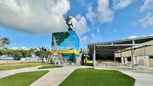 Um edifício com um mural de uma árvore e uma escultura de peixe no topo.