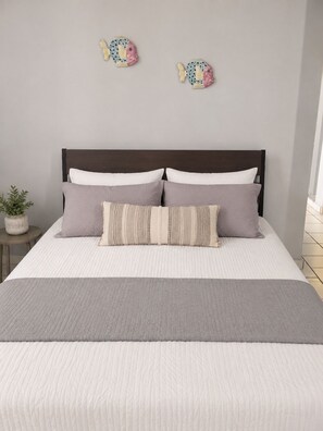 A bed with a dark headboard, multiple pillows, and a gray blanket.