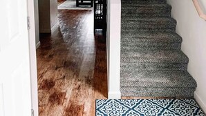 Un escalier muni d’une rampe, menant à un palier où se trouve un tapis à motifs.