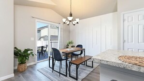 Uma cozinha moderna com bancada de granito, área de refeições com mesa e cadeiras, e luminária pendente.