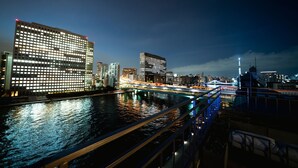 Un paisaje urbano con edificios iluminados, un río y un puente.
