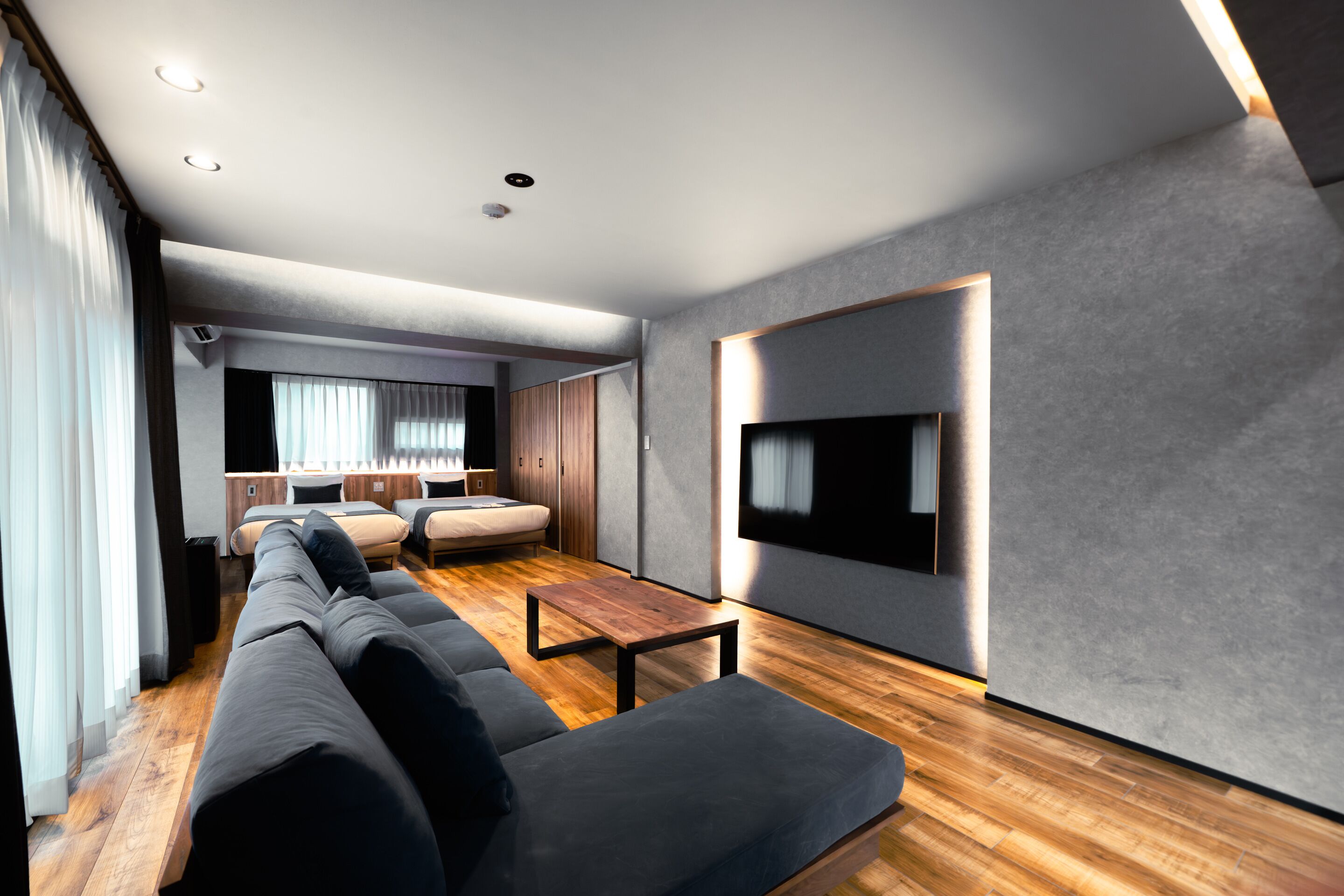 A modern living room with a sofa set, a TV mounted on the wall, and a wooden coffee table.