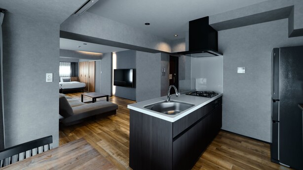 Una cocina moderna con una isla central, electrodomésticos integrados y un rincón comedor con sofá y mesa.