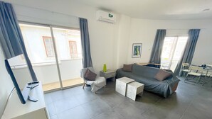 Una sala de estar moderna con un sofá, una mesa de centro y un televisor sobre un mueble.
