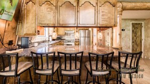 Una cocina con armarios de madera, una isla de mármol y taburetes de bar.