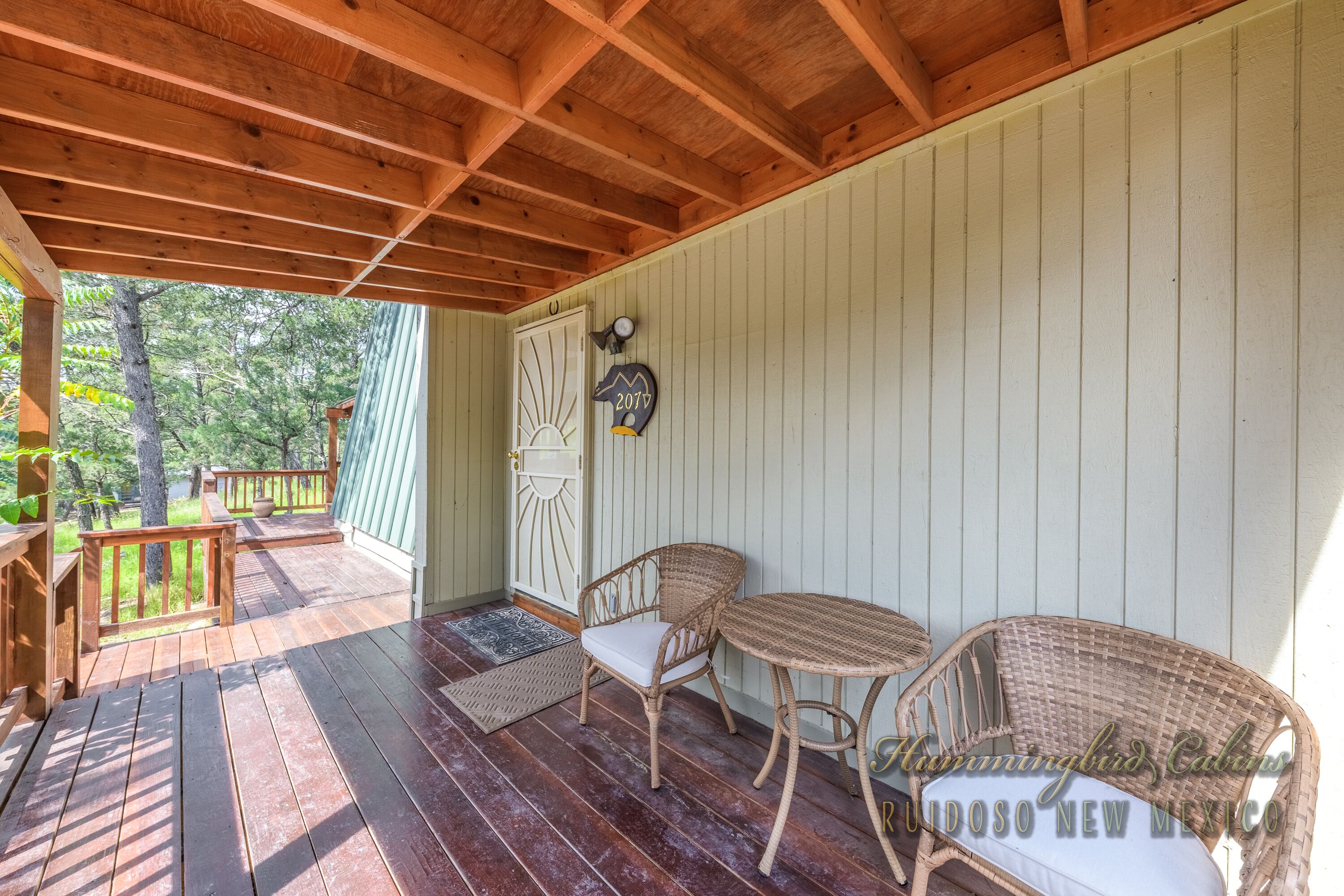 A wooden deck with wicker furniture and a door with a sun design.