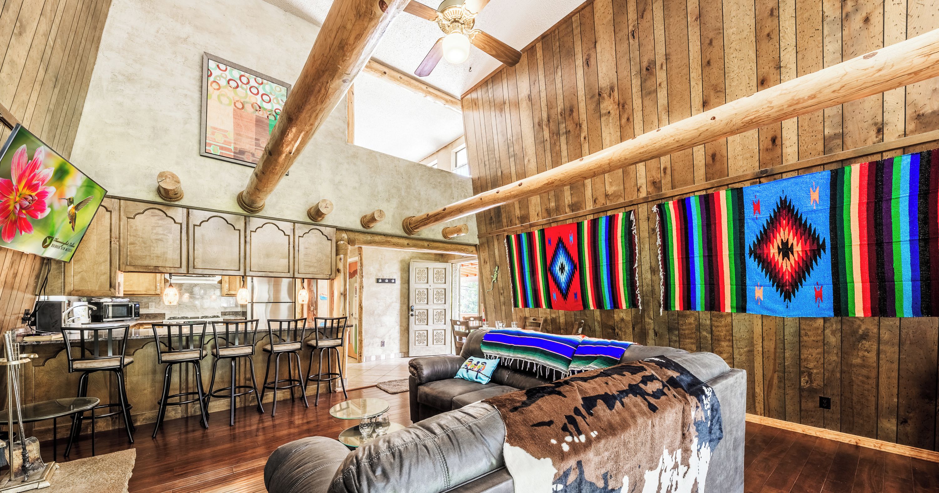 A spacious living area with a large couch, wooden walls, and a bar area.