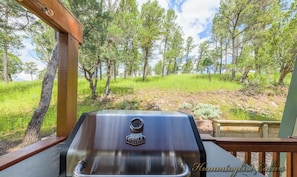 A grill on a wooden deck with a view of a forested area. - Hidalgo Haven | Santa Fe Style, Mountain Air & Wildlife Views (Ruidoso)