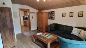 Una sala de estar con una mesa de centro de madera, un sofá verde oscuro con cojines estampados y un aparador de madera.