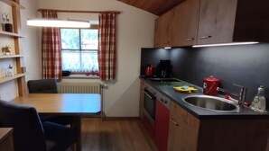 Una cocina compacta con una mesa, sillas, un radiador, una estufa y un lavabo.