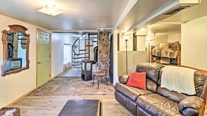 Un salon chaleureux avec un canapé en cuir, une cheminée en pierre et un escalier menant à un autre niveau.