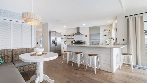 A modern kitchen with a central island, white cabinetry, and a hanging light fixture.