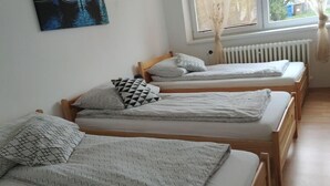 Una stanza con tre letti in legno, ognuno con un materasso bianco e cuscini decorati.