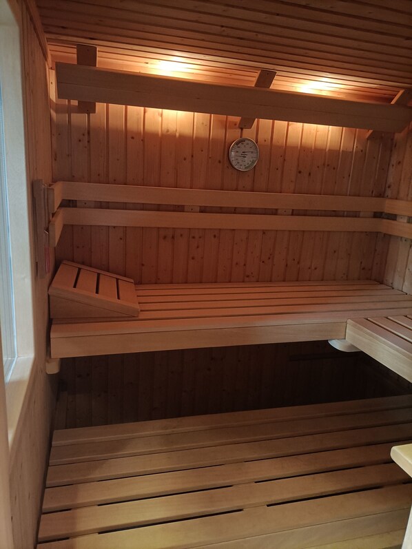 A sauna with wooden benches and a thermometer on the wall.