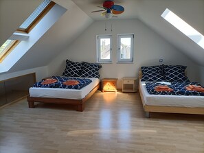 A bedroom with two beds, a skylight, and a ceiling fan.