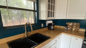 Una cocina con un lavamanos doble, una cafetera y una encimera de madera.