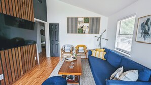 Una sala moderna con un sofá azul, suelo de madera y una mesa de centro.