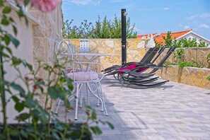Relax on the patio with a choice of seating, featuring a metal chair and a lounge chair, and a table for dining or relaxation.
