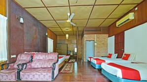 A hotel room with a sofa, two single beds, a ceiling fan, an air conditioning unit, and a wooden door. - OYO 90595 Pelangi Beach Resort Cherating (Cherating)
