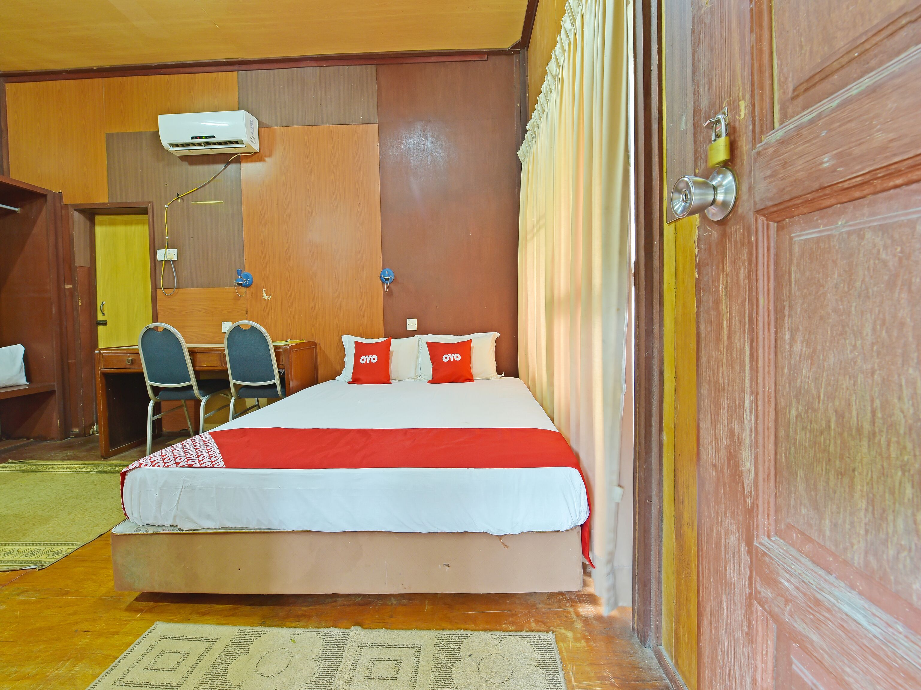 Une chambre d’hôtel avec un lit, deux chaises, un bureau et une armoire.