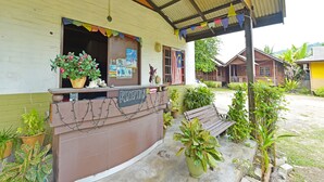 A reception area with a sign, potted plants, and a wooden bench. - OYO 90595 Pelangi Beach Resort Cherating (Cherating)