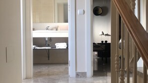 A hallway leading to a bathroom with a sink and mirror.