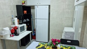A compact kitchen with a microwave, refrigerator, and a small dining table with a cow-themed tablecloth. - Stadion apt 2 Near Athens city center (Athina)