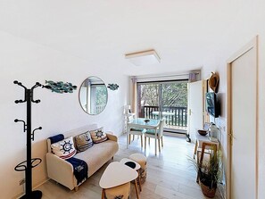 Ein gemütlicher, kleiner Wohnraum mit Sofa, Esstisch und Garderobe.