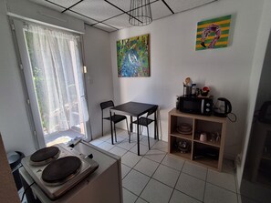Eine kleine Küche mit Esstisch, Stühlen, einer Mikrowelle und einer Kaffeemaschine.