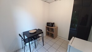 Habitació petita amb taula i cadires, microones, un armariet petit i una finestra.