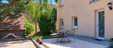 A residential building with a patio, outdoor seating, and a garden.