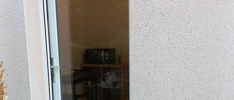 Puerta corrediza de vidrio que da a un espacio interior con piso de baldosas, una mesa y sillas a la vista.