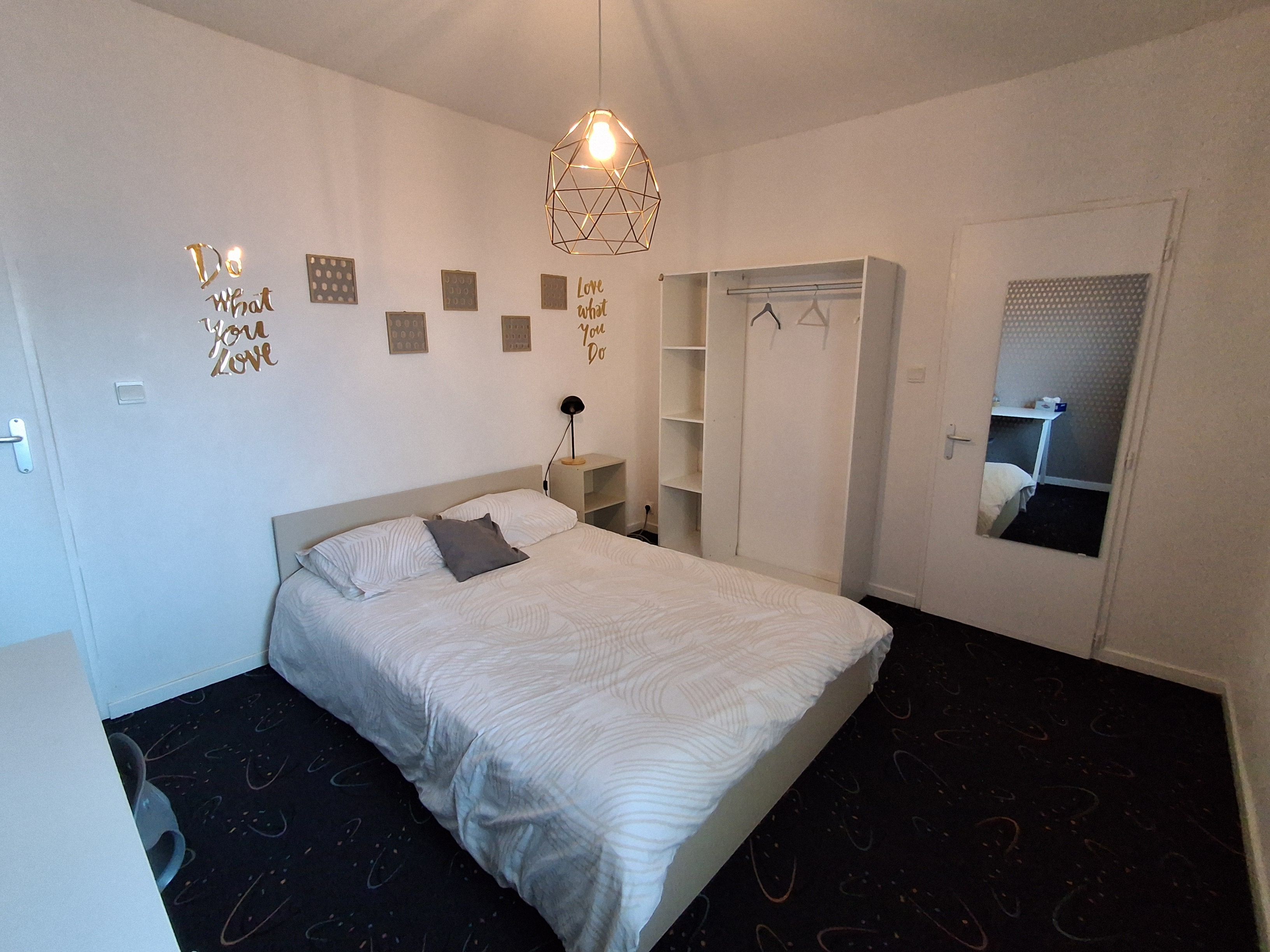 Une chambre à coucher comprenant un lit, une armoire, un miroir et des œuvres d’art murales inspirantes.