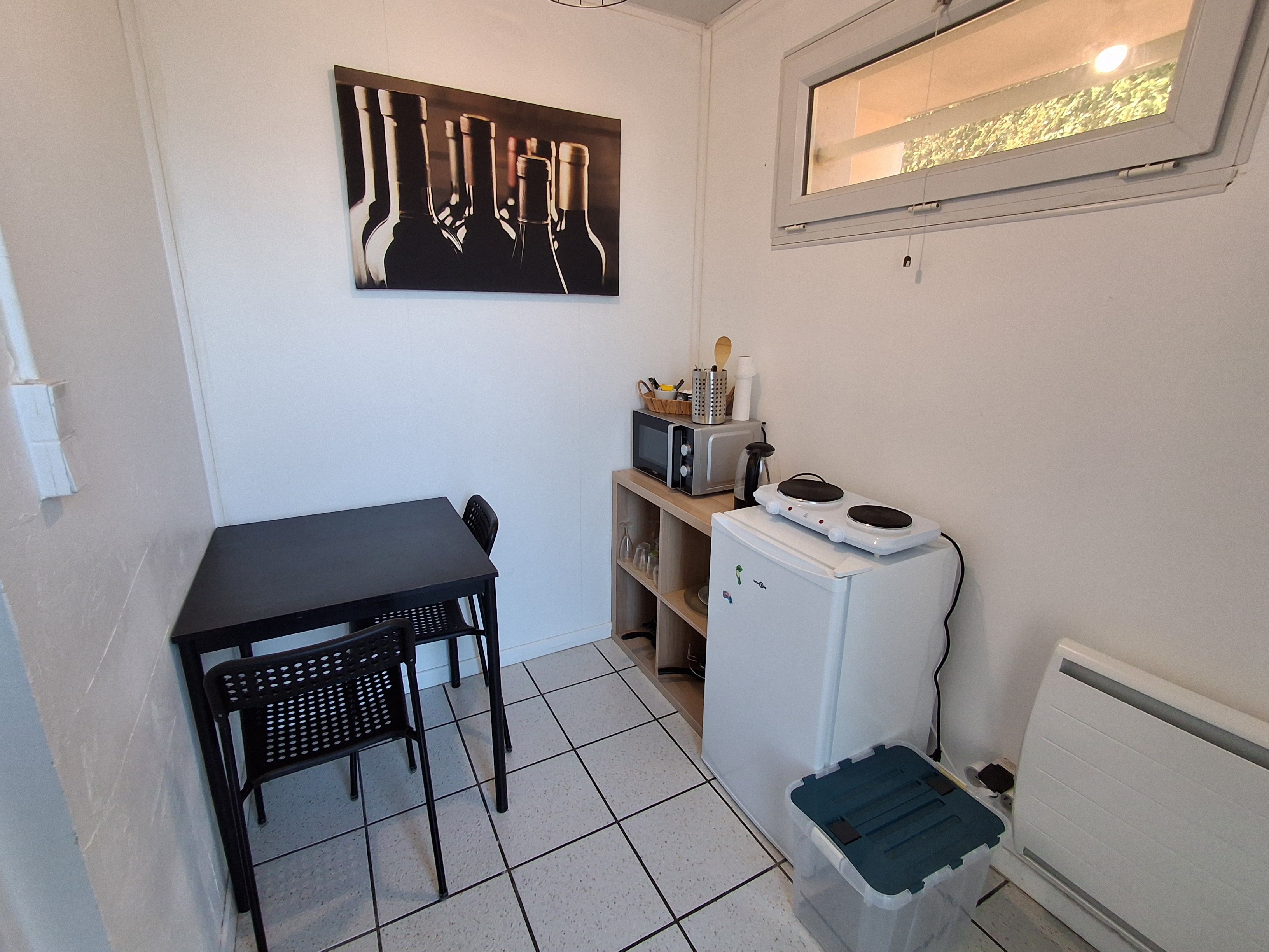 A small kitchenette with a microwave, a refrigerator, a sink, and a dining area with a table and chairs.