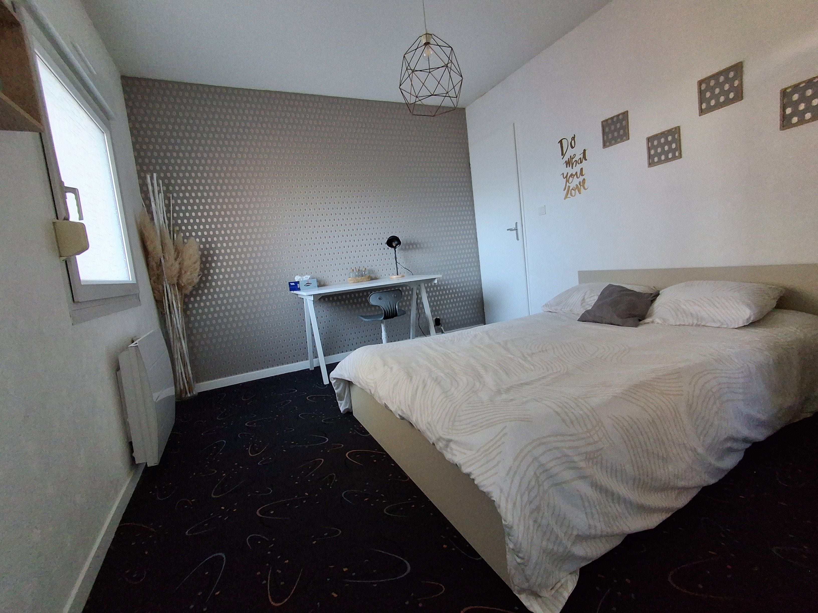 Un dormitorio con cama, escritorio y ventana.