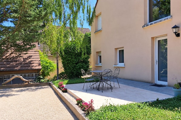 A residential building with a patio, outdoor seating, and a garden.