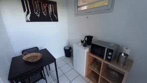 A compact kitchenette with a microwave, a small refrigerator, a sink, and a dining area with a table and chairs. - Charming Studio - Sleeps 2 - Terrace & Parking (Dijon)