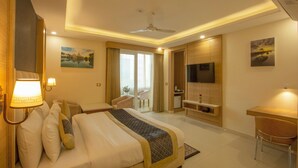A hotel room with a bed, desk, TV, and a balcony with a chair. - Hotel Sakura by Maps, GURGAON (Gurugram)