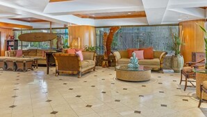 A spacious lobby with a high ceiling, wooden paneling, and a large window offering a view of greenery. - Spacious Partial Ocean View W/Lanai and A/C - Bamboo Waikīkī Hotel #1006 (Honolulu)