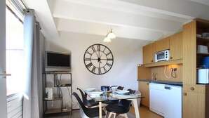 Una cocina compacta con comedor, armarios de madera, un microondas y un reloj de pared grande.