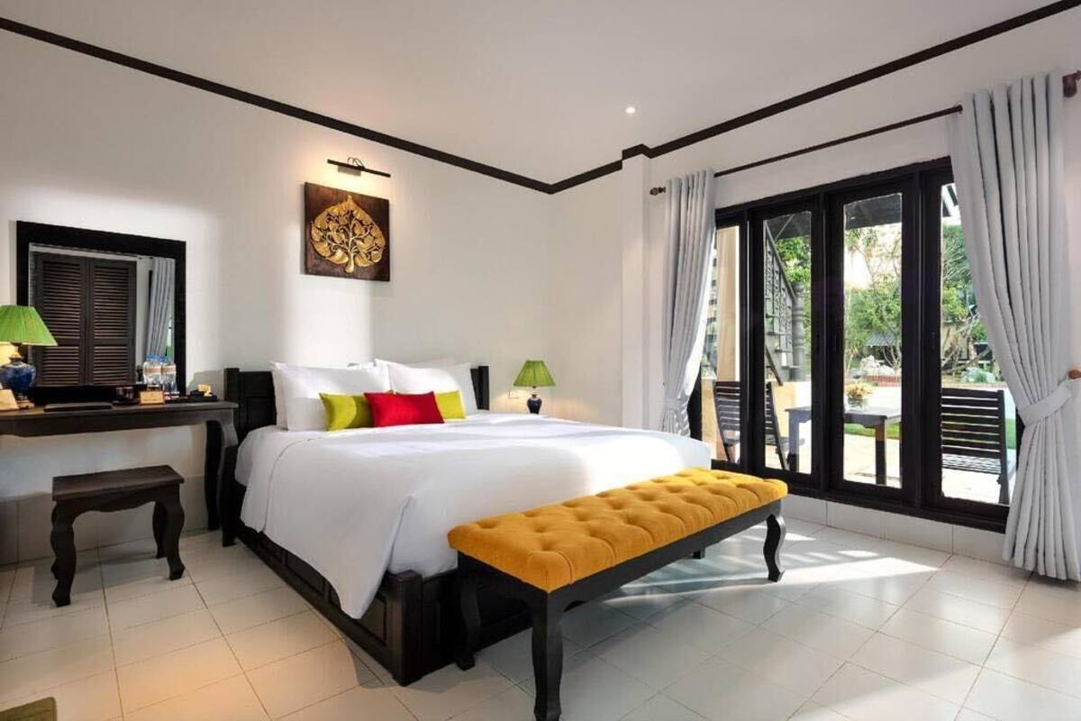 Camera d'albergo con un letto grande, una panca, una scrivania e vista sull'esterno.