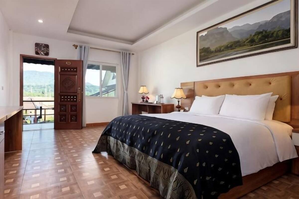 Una camera d'albergo con un letto, comodini, una scrivania e un'ampia finestra vista montagna.