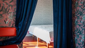 Una habitación con cama, una silla y cortinas azules.