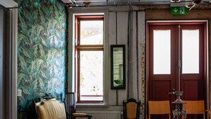 Una habitación con piso de madera, un papel tapiz estampado, una ventana y una puerta con letrero de salida de emergencia.