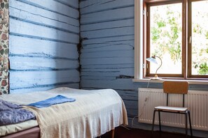 Ein Zimmer mit einem Bett, einem Sessel, einem Fenster und Blick ins Grüne sowie einer Heizung.